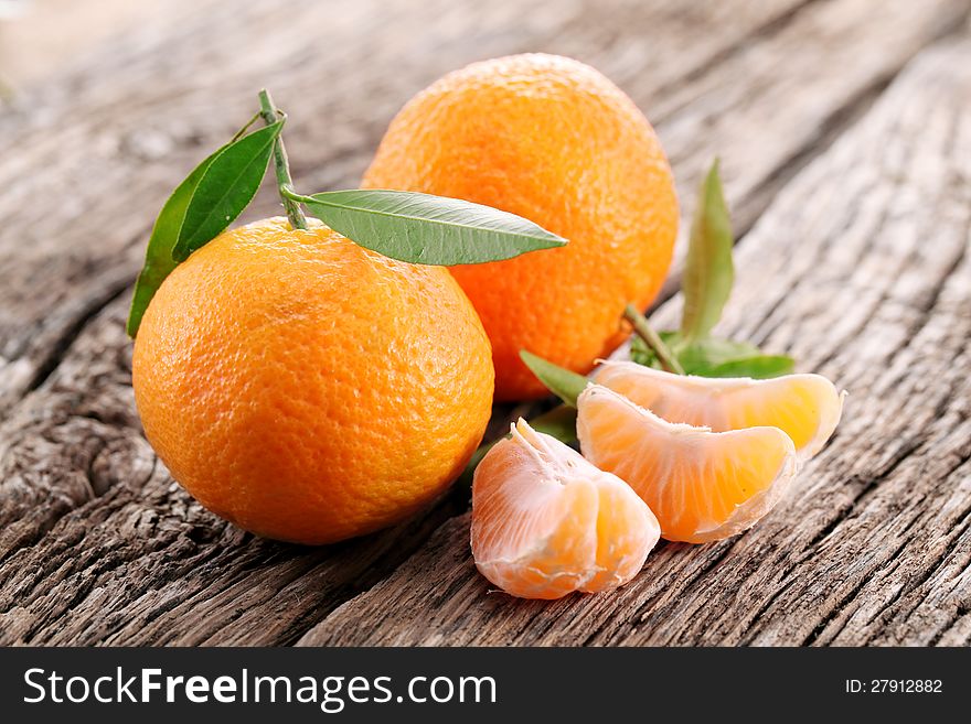 Tangerines with leaves on a wooden table.