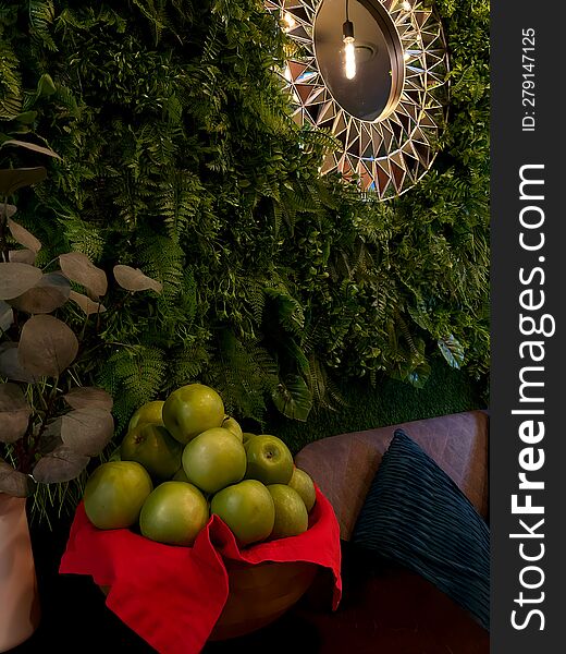 Green Apples In A Plate Near The Wall With Plants