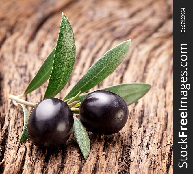 Ripe black olives with leaves on a wooden background. Ripe black olives with leaves on a wooden background.
