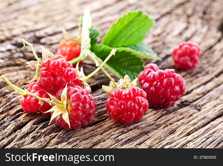 Raspberries with leaves on the old wooden table.