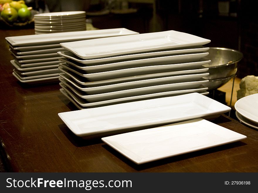 Lots of big plates stack up in a restaurant to for the coming dinner time. Lots of big plates stack up in a restaurant to for the coming dinner time.