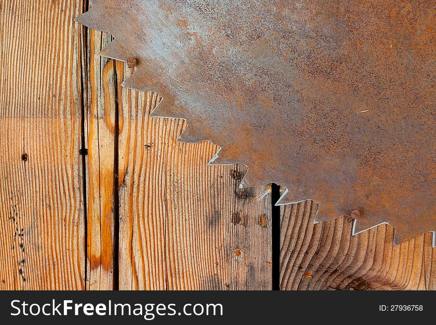 A rusty saw blade is hung on a wood wall to create an interesting and unique abstract background image with plenty of copy space for design. A rusty saw blade is hung on a wood wall to create an interesting and unique abstract background image with plenty of copy space for design.