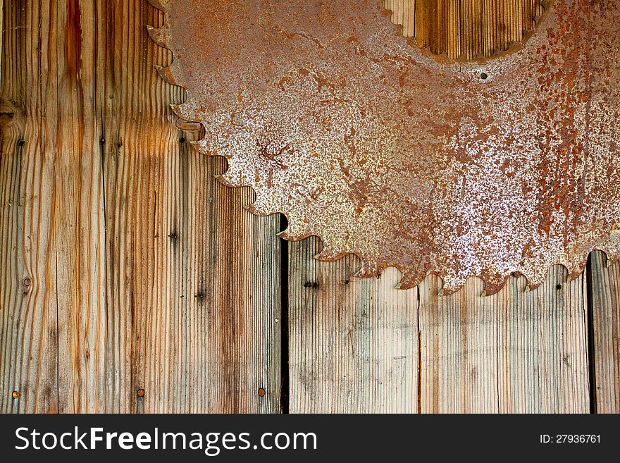 A rusty saw blade is hung on a wood wall to create an interesting and unique abstract background image with plenty of copy space for design. A rusty saw blade is hung on a wood wall to create an interesting and unique abstract background image with plenty of copy space for design.