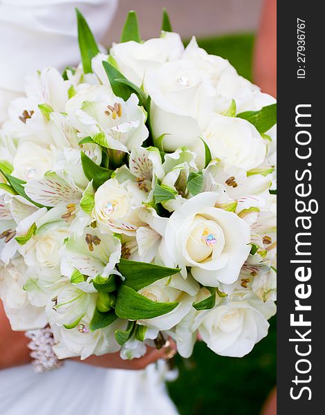 A bride holds her bouquet of flowers at a wedding ceremony while wearing a white dress. A bride holds her bouquet of flowers at a wedding ceremony while wearing a white dress.