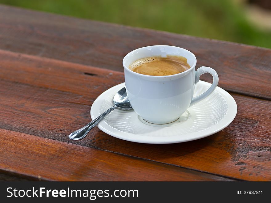 Coffee in a white mug on a wooden table in the garden.