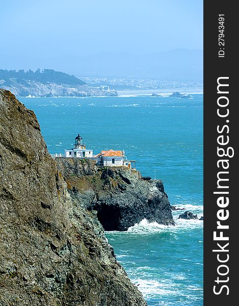 Lighthouse on the cliff and city in the fog on the background in California, USA. Lighthouse on the cliff and city in the fog on the background in California, USA