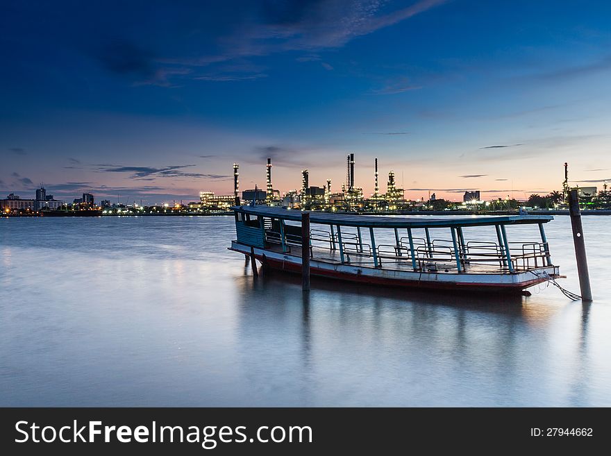 Boat With Oil Refinery At Twilight