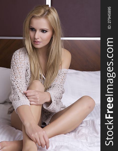 Beautiful young blonde woman in sweater on the bed. Beautiful young blonde woman in sweater on the bed