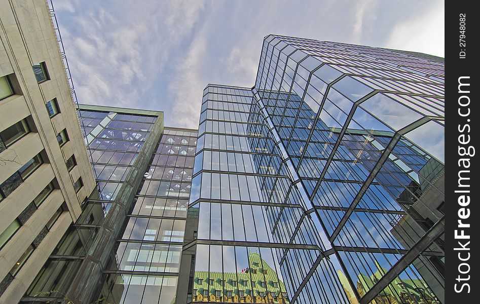 West Wing of Parliament Buildings reflected in glass of modern building in Ottawa, Canada