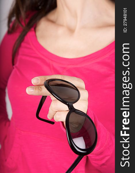 Woman pink shirt detail holding a black sunglasses. Woman pink shirt detail holding a black sunglasses