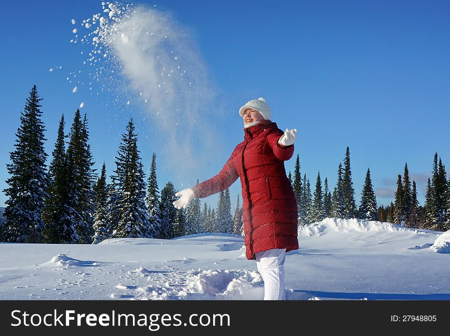 Girl throws snow up in a sunny afternoon.