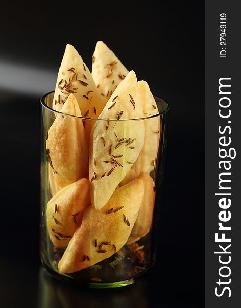 Crispy snacks with caraway seeds in a glass on black background. Crispy snacks with caraway seeds in a glass on black background