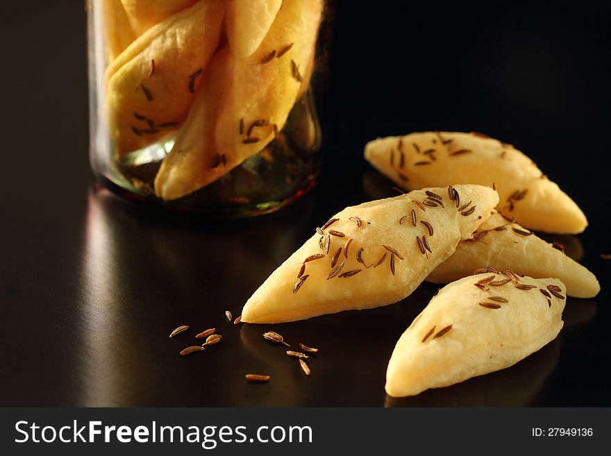 Crispy snacks with caraway seeds in a glass on black background. Crispy snacks with caraway seeds in a glass on black background