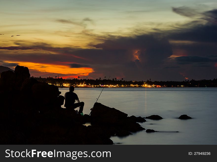 Silhouette fisherman catching a fish on sea