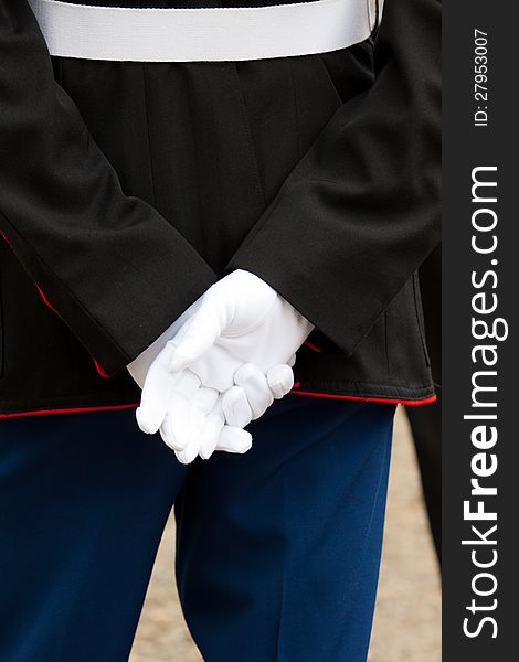A marine soldier stands at attention during a wedding ceremony with his hands behind his back wearing full uniform and white gloves. A marine soldier stands at attention during a wedding ceremony with his hands behind his back wearing full uniform and white gloves.