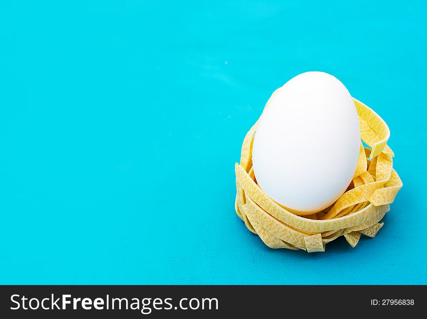 Italian pasta nest with egg, on blue background