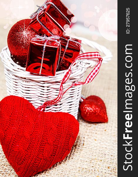 Woolen heart and tiny red presents in a white wicker basket