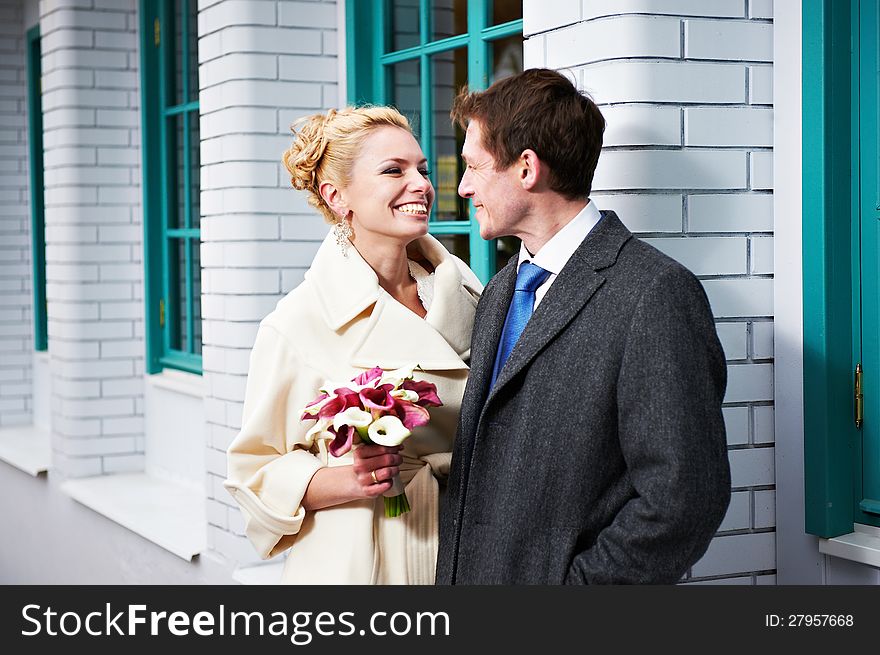 Happy bride and groom near white building