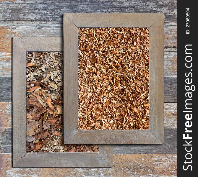 Sawdust and dry leaves in a wooden frame on a wooden background. Sawdust and dry leaves in a wooden frame on a wooden background.