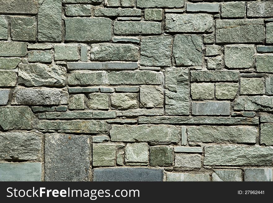 Abstract architectural background with a cut stone wall of irregular rectangular blocks with a rough textured surface