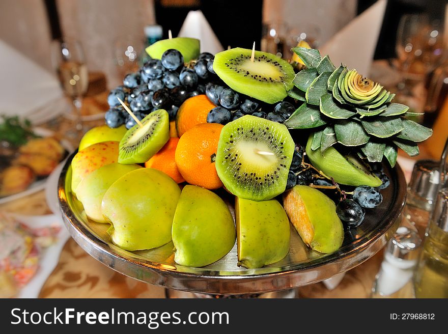 Fresh fruits attractively served to the table-grapes, kiwi ,apples,tangerines