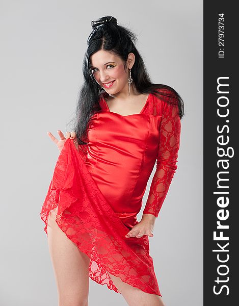 Portrait of a beautiful young brunette in a burning scarlet dress pose in the studio. Portrait of a beautiful young brunette in a burning scarlet dress pose in the studio