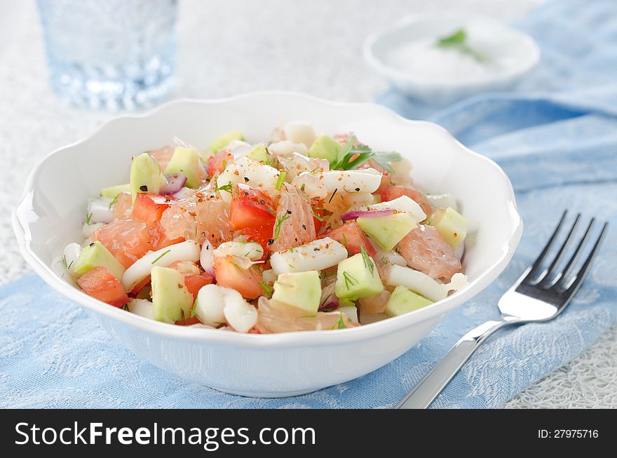 A bowl of salad with squid, avocado and grapefruit, closeup. A bowl of salad with squid, avocado and grapefruit, closeup
