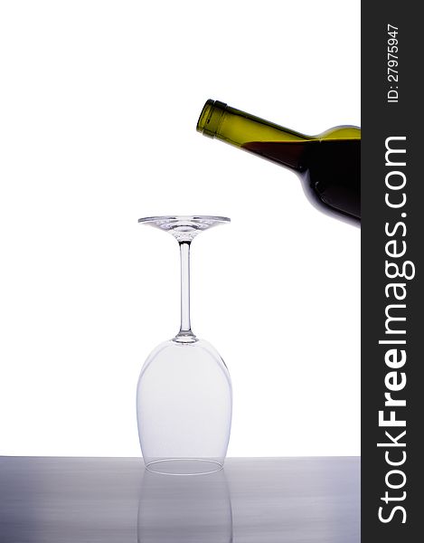 Inverted empty wine glass and bottle of red wine isolated on white background