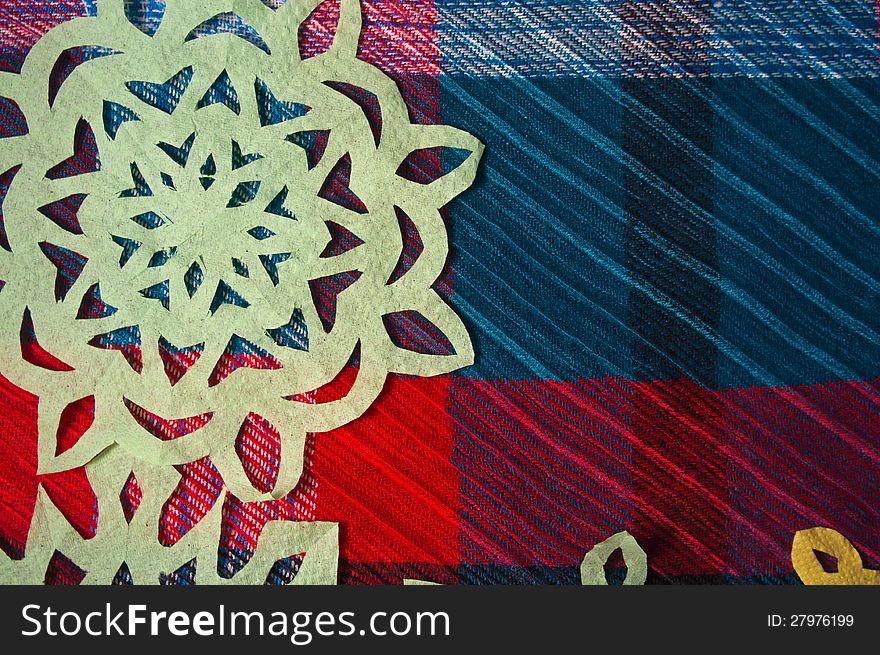 Winter background with handmade paper snowflakes on wool tartan fabric