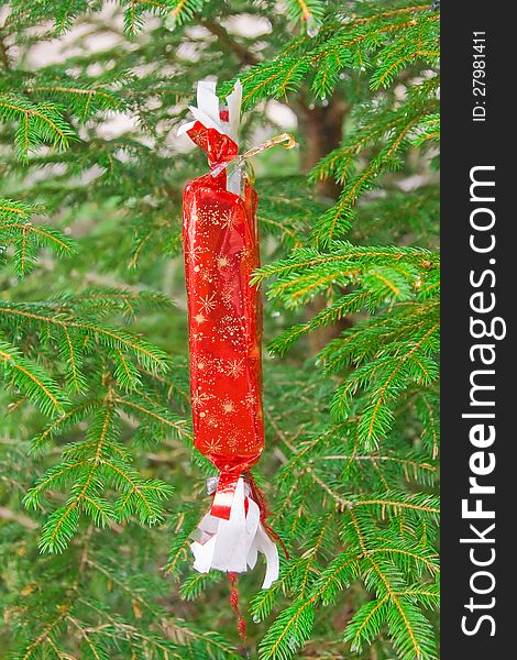 Christmas gift in red wrapping hanging on the Christmas tree