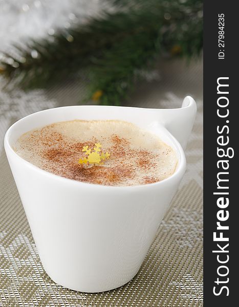 Cup of cappuccino on the table, fir branches in the background