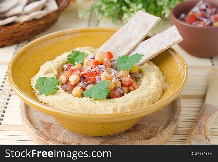 Hummus with a salad of chickpeas and tomatoes with cilantro and crackers closeup