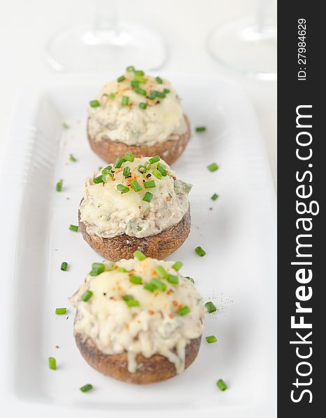 Stuffed mushrooms, baked with cheese and herbs on white dish, selective focus