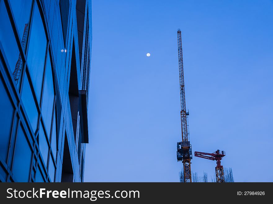 High business building with metal crane and full moon in sky at dawn. High business building with metal crane and full moon in sky at dawn