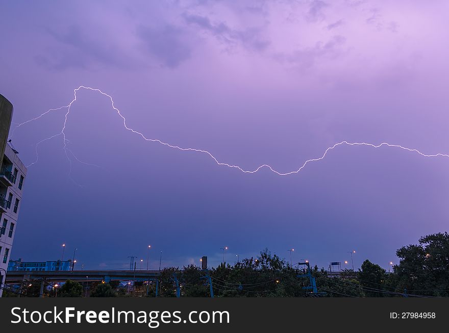 Lightning strike over city sky at twilight
