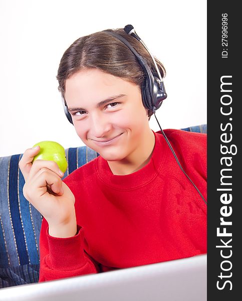 Teenage boy using laptop and eating apple