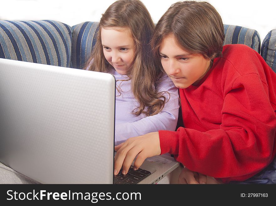 Brother and sister playing games on laptop at home