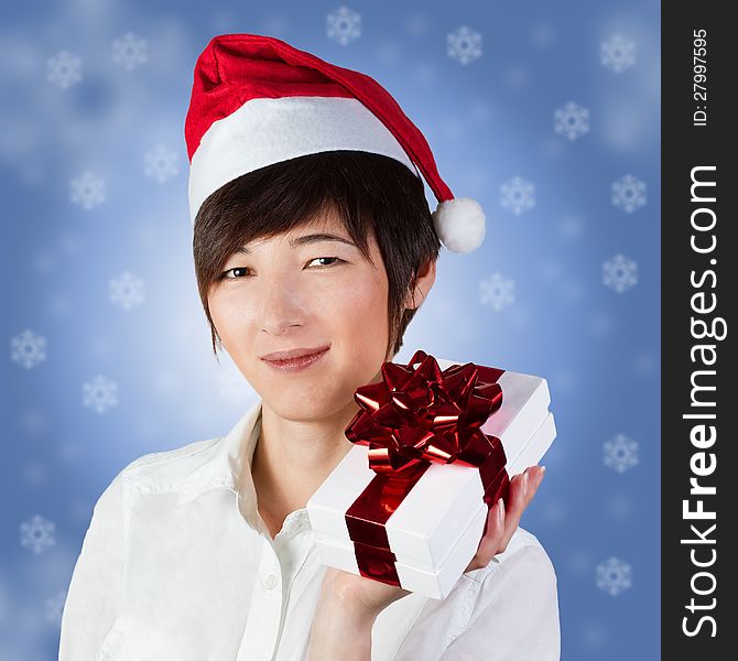 Beautiful smiling woman in Santa hat with gift box on blue background