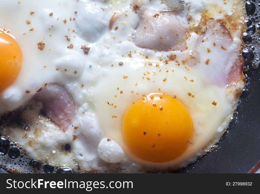 Close-up shot of an egg being fried on a pan with bacon. Close-up shot of an egg being fried on a pan with bacon