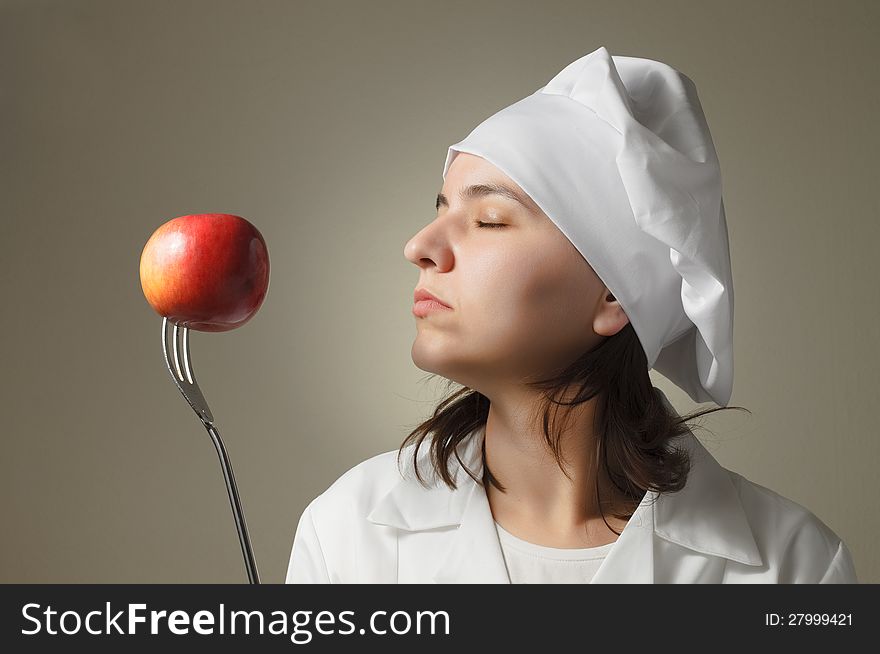 Chef woman enjoying the smell of an apple. Chef woman enjoying the smell of an apple