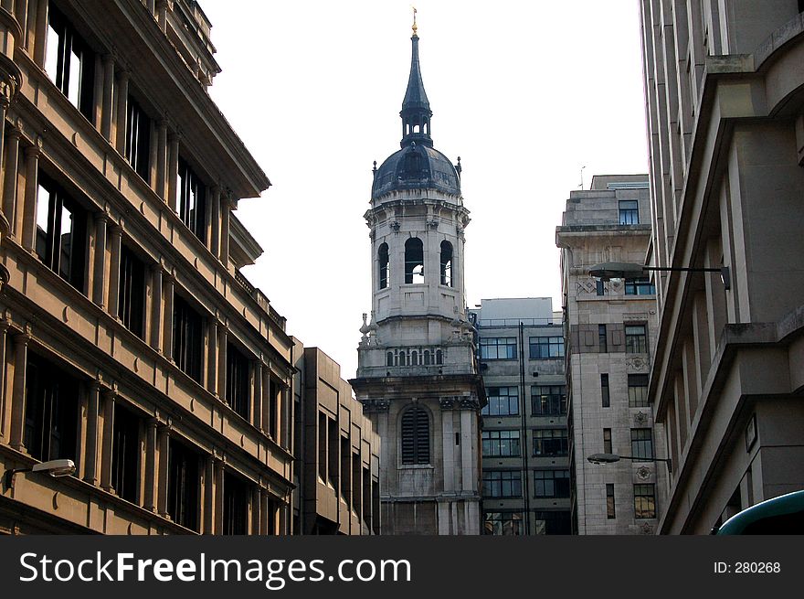 This is an image of a bell tower, in the midst of city buildings. This is an image of a bell tower, in the midst of city buildings.