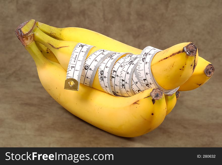 Bananas With a Tape Measure Wrapped Around It. Diet Concept - Clipping Path Included. Bananas With a Tape Measure Wrapped Around It. Diet Concept - Clipping Path Included