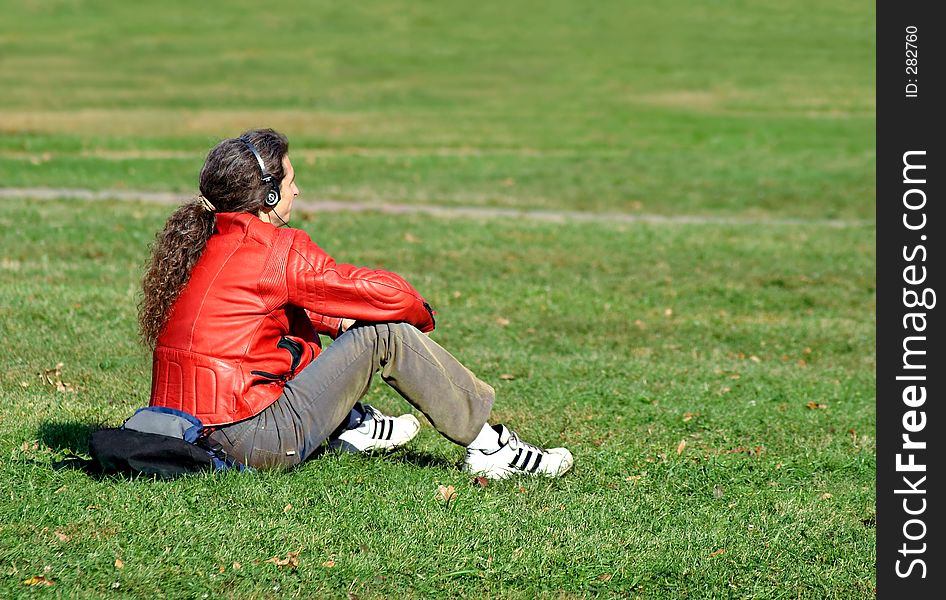 The guy has a rest on a grass and listens to music. The guy has a rest on a grass and listens to music