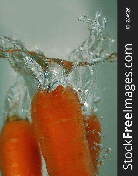 Carrots dropped in water with a refreshing splash. Carrots dropped in water with a refreshing splash