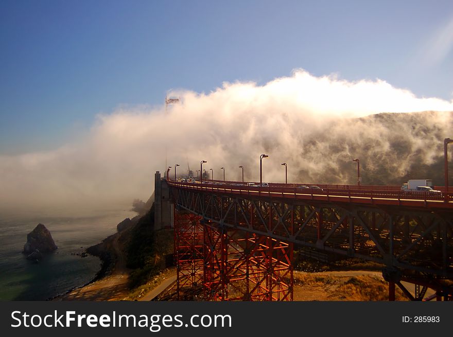 Sunlit fog flowing over the Golden Gate Bridge in the late afternoon.