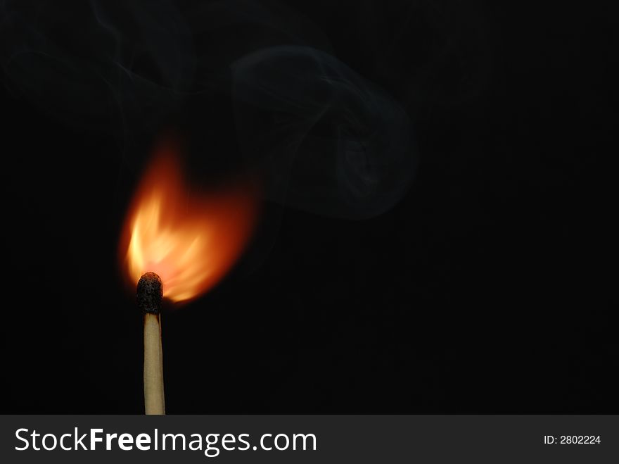 Photo of a burning match with smoke on a black background