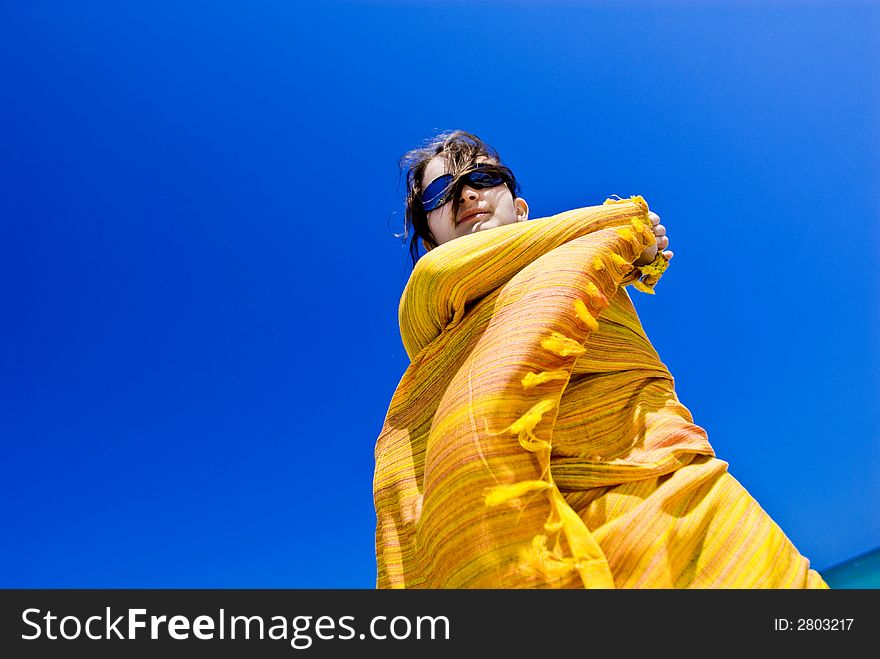 Beautiful young girl wrapped in yellow scarf against clear blue sky. Beautiful young girl wrapped in yellow scarf against clear blue sky.