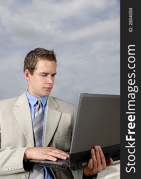Young businessman with laptop in his hands outdoor.