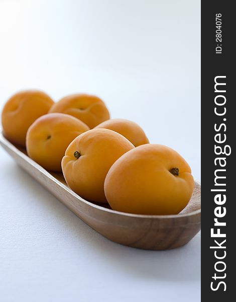 Group of apricots in a wooden bowl waiting to be eaten. A sweet healthy snack,