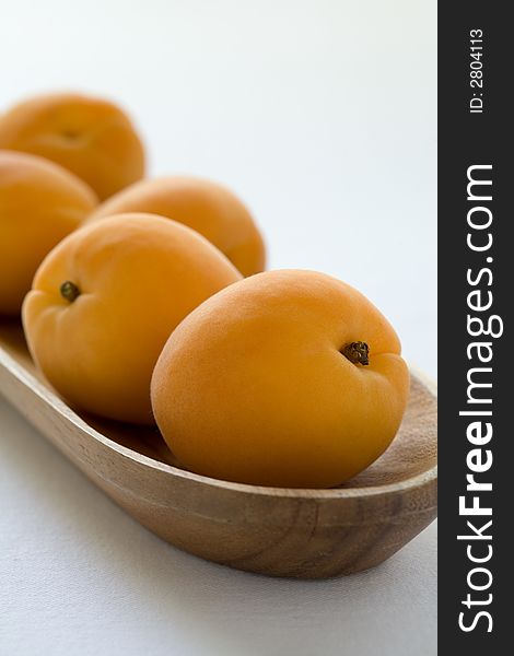 Group of apricots in a wooden bowl waiting to be eaten. A sweet healthy snack,